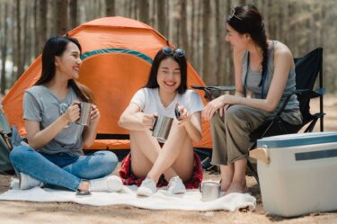 group of young asian friends camping or picnic together in forest